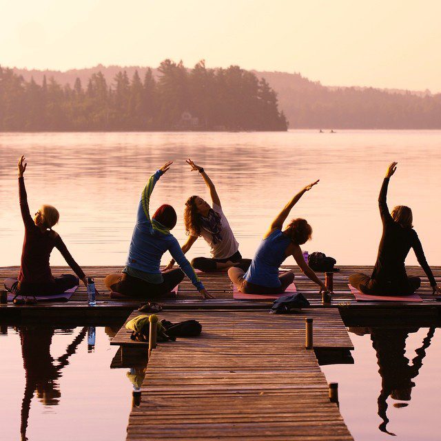 5 women doing yoga on a dock