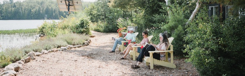 reading and sitting quietly in muskoka chairs by the waterfront