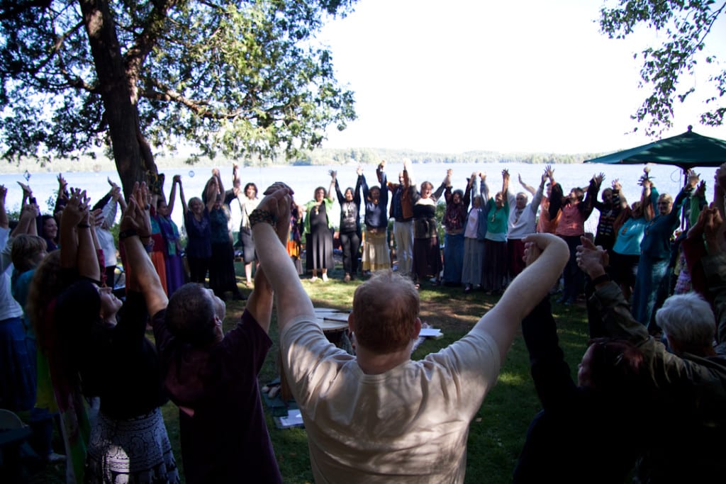 circle with hands raised at the lakefront